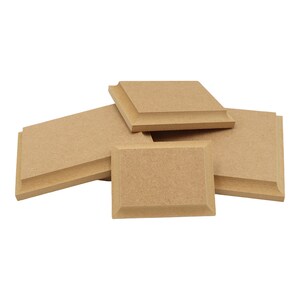 May include: Four beige square acoustic panels with bevelled edges. The panels are made of a textured material and are stacked on top of each other.