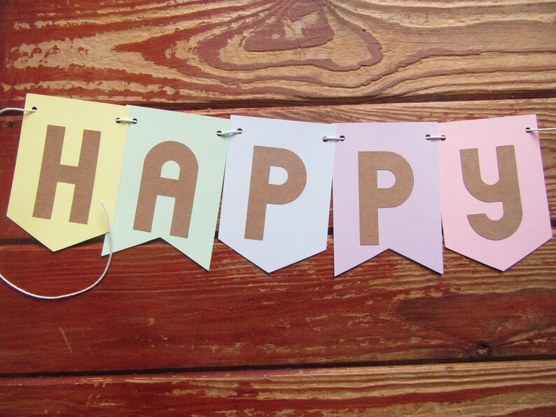 Pode incluir: Uma faixa de cores pastel com a palavra "HAPPY" escrita em letras marrons. Cada letra est&aacute; em uma bandeira separada com a parte inferior pontiaguda.