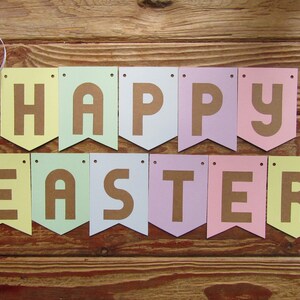 Pode incluir: Uma faixa de cores pastel com as palavras "Happy Easter" em letras marrons. A faixa &eacute; feita de papel e tem uma borda festonada.
