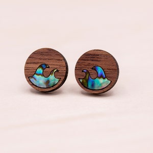 May include: A pair of wooden earrings with a wave design. The waves are made of iridescent abalone shell.