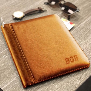May include: A brown leather journal with the name "BOB" embossed on the front cover.