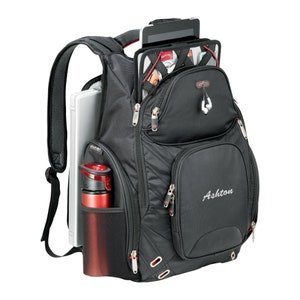 May include: Black backpack with red accents and a zippered pocket that says "Ashton". The backpack has a laptop compartment, a water bottle holder, and a pocket for a tablet.