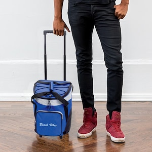 May include: A blue rolling cooler bag with a black handle and wheels. The bag has a white zipper and a black strap. The bag has the text "Beach Vibes" printed on the front.
