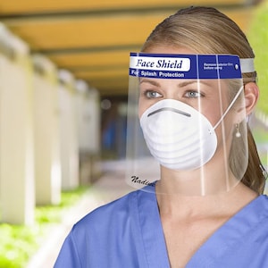 May include: A clear face shield with a blue band that reads "Face Shield For Splash Protection." The shield is worn with a white mask. The text "Remove exterior film before using" is also visible.