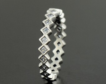 May include: A silver ring with a row of clear square-shaped stones set in a zig-zag pattern.
