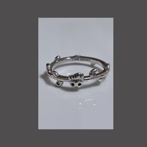 Könnte beinhalten: Ein silberner Ring mit einer Groot-Figur aus Guardians of the Galaxy. Der Ring ist mit kleinen Blättern verziert und die Worte "I am Groot" sind in die Band graviert.