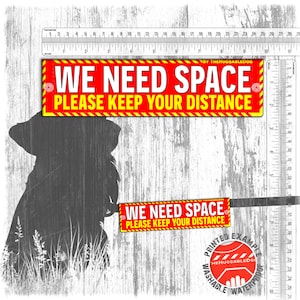 May include: A red and yellow sign with the text "WE NEED SPACE PLEASE KEEP YOUR DISTANCE". The sign is shown with a silhouette of a dog and a ruler in centimetres.