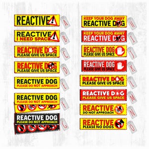 May include: A selection of rectangular yellow and red warning signs with black text, including "REACTIVE DOG" and "PLEASE GIVE US SPACE." Some signs feature a dog silhouette or a hand symbol. Each sign has a tag.