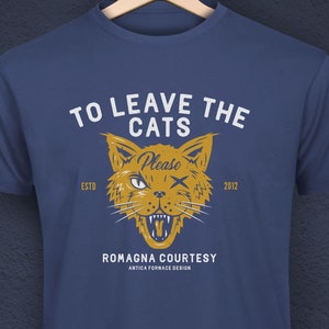 Könnte beinhalten: Marineblaues T-Shirt mit einer Grafik einer zwinkernden Katze und dem Text "TO LEAVE THE CATS Please" in Weiß. Die Katzengrafik ist gelb und trägt den Text "ESTO 2012" über und unter der Katze. Das Shirt hat auch den Text "ROMAGNA COURTESY" und "ANTICA FORNACE DESIGN".