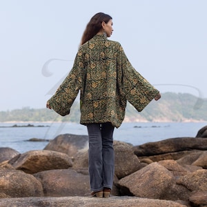 Back view of emerald floral hand block-printed velvet kimono jacket featuring wide sleeves and relaxed silhouette. Captured near the sea, it highlights the handcrafted pattern and easy drape of this ZinniaPearl boho design.