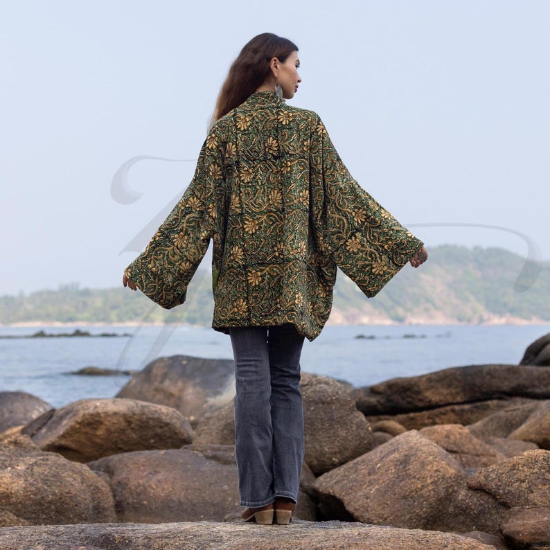 Back view of emerald floral hand block-printed velvet kimono jacket featuring wide sleeves and relaxed silhouette. Captured near the sea, it highlights the handcrafted pattern and easy drape of this ZinniaPearl boho design.