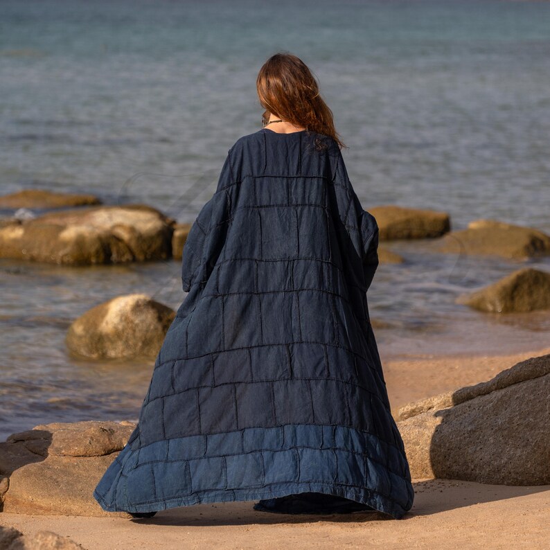 Back view of the Midnight Indigo blue robe. The patchwork construction is clearly visible, with a subtle design detail at the hem where a lighter blue panel creates a two-tone effect. The maxi length creates a sweeping, dramatic exit.