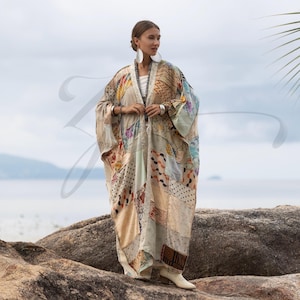 Peut inclure: Un long kimono patchwork fluide dans les tons beige, crème et pastel. Le kimono présente une variété de carrés de tissu à motifs et est porté sur un haut et un pantalon blancs. Le vêtement a des manches longues et est ouvert sur le devant.