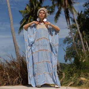 May include: A light blue maxi dress with a crocheted design and a white crocheted trim. The dress has a loose, flowing fit and is perfect for a beach vacation.