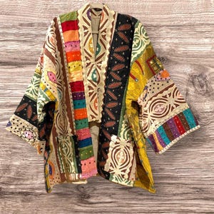 May include: A colourful patchwork kimono with a variety of patterns and textures. The kimono is made of a lightweight fabric and has a relaxed fit.