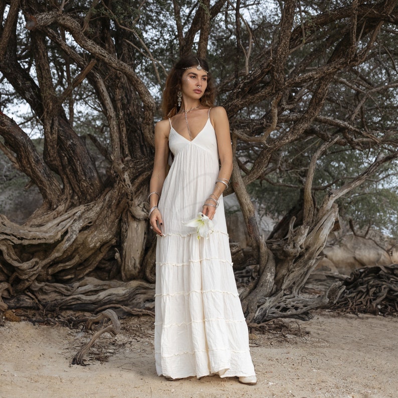Boho beach wedding dress with tiered raw cotton silhouette, deep V-neck, and smocked back. This ZinniaPearl design is breathable, unlined, and one-of-a-kind, with thin self-tie straps and a minimalist, earthy look. Perfect for barefoot brides, elopements, and bohemian celebrations. Made to fit multiple sizes including plus, with soft ivory-beige tones and natural texture.