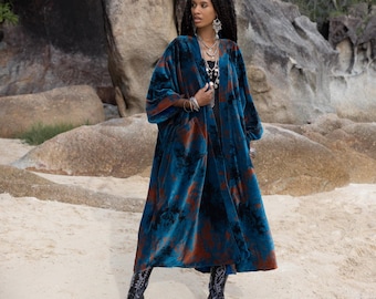 May include: A long, flowing blue and rust-colored velvet robe with a tie closure. The robe has a loose, relaxed fit and features a unique tie-dye pattern.