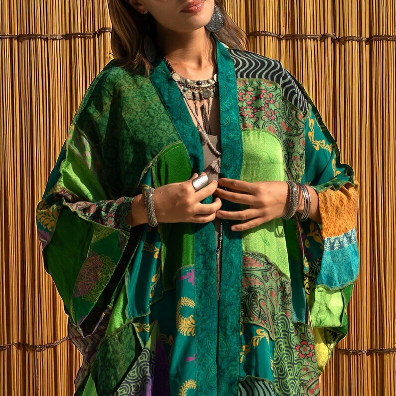 Close-up detail of the Harper Jade Emerald Oasis Kimono, showing the intricate patchwork of upcycled vintage silk saris in emerald green, teal, saffron, and patterned motifs. The lightweight silk fabric and bohemian cut emphasize artisan craftsmanship. Styled with silver jewelry, this eco-friendly kimono robe is designed for festivals, layering, and timeless boho elegance.