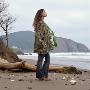 Side profile of model in green floral embroidered kimono jacket with contrast printed lining, wide sleeves, and relaxed fit — handmade boho outerwear by ZinniaPearl.
