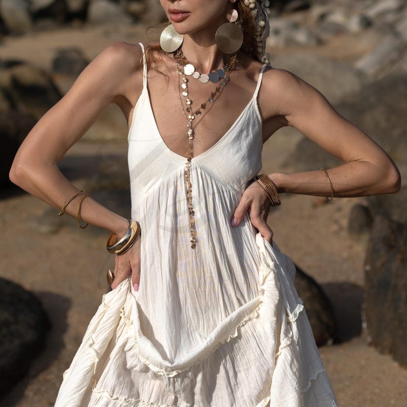Feel grounded and radiant in this raw cotton bridal dress designed for wild-hearted women and earthy celebrations. With adjustable straps, a smocked bodice, and flowing skirt tiers, Savita offers both freedom and femininity. This breathable, handmade gown is ideal for beach weddings, eco-conscious brides, or spiritual gatherings. Its unlined silhouette invites styling with nude slips or swimwear for an ethereal, non-synthetic bridal look.
