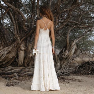 Ethical and elegant, this ZinniaPearl boho wedding dress is made from raw cotton with a plunging neckline, smocked stretch-back waist, and flowy tiered skirt. Unlined and lightweight, it’s perfect for destination weddings or outdoor elopements. Fits a wide range of sizes with comfort and beauty, including plus size brides. A soulful gown for barefoot ceremonies.