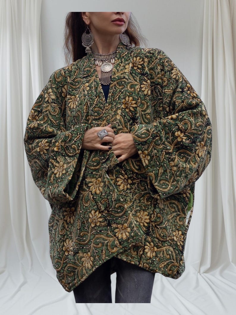 Close-up of emerald green and gold floral velvet kimono jacket showing detailed hand block print, soft texture, and artisan craftsmanship with layered silver jewelry accents.
