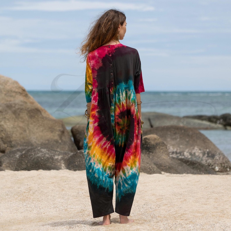 Hand-dyed boho jumpsuit for curvy bodies, made from soft jersey cotton with a relaxed harem silhouette. Firewheel Sunset colorway offers rich magenta, gold, and turquoise swirls. Ideal as a beach cover-up, loungewear, or festival outfit. A bold and soulful plus size romper that celebrates handmade, artistic fashion.