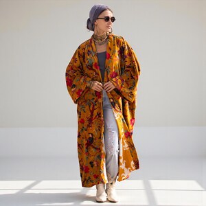 Full body shot of the Mai velvet duster styled with jeans and boots. The coat hangs open, revealing the comfortable, wide fit suitable for plus sizes (72 inch bust). The inner lining is visible at the hem, showing quality construction. A versatile statement piece for fall and winter layering.
