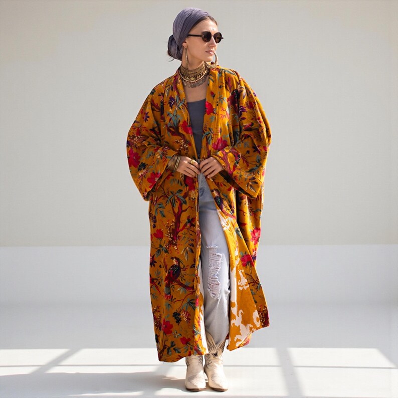 Full body shot of the Mai velvet duster styled with jeans and boots. The coat hangs open, revealing the comfortable, wide fit suitable for plus sizes (72 inch bust). The inner lining is visible at the hem, showing quality construction. A versatile statement piece for fall and winter layering.