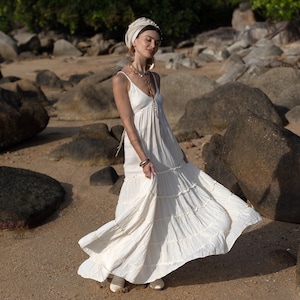 Celebrate your love story in a raw cotton elopement gown made for ocean breezes and golden light. The Savita Dress blends a minimalist aesthetic with artisan detail—featuring a plunging neckline, self-tie straps, and an airy tiered silhouette. Ideal for barefoot brides and festival goddesses, this unlined cotton maxi gown is soft, breathable, and entirely handmade. A poetic choice for maternity portraits, beach engagements, or summer ceremonies.