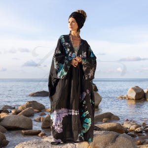 May include: A long, black, tie-dye robe with blue and purple accents. The robe is worn by a person standing on a rocky beach.