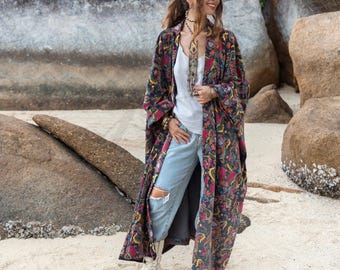 May include: A long, black, floral patterned kimono with a white tank top and light blue jeans. The person is wearing white cowboy boots.