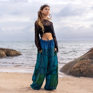 May include: A black long-sleeved, open-knit cropped top paired with loose-fitting, wide-leg trousers featuring a patchwork design in various shades of blue and green, complete with an elastic drawstring waistband and side pockets.