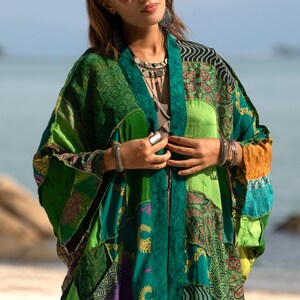 Close-up of the Harper Jade Kimono in Emerald Oasis, showing the luxurious patchwork of upcycled silk saris with emerald, teal, saffron, and patterned motifs. The wide kimono sleeves and artisan-made details reflect the craftsmanship of this unique bohemian robe. Featherlight, soft silk makes it an ideal layering piece for festivals, resort wear, and everyday boho style.