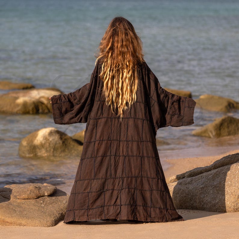 Back view of the Cocoa Earth patchwork robe. Shows the massive, grand scale of the garment. The monochrome patchwork panels are stitched together with raw, exposed seams, creating a structured, geometric look. The fabric has a crinkled, vintage finish that adds depth to the deep brown earth tone.