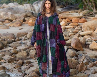 May include: A long, patchwork hooded coat with a mix of purple, green, red, and black squares. The coat is made of a soft, velvety fabric and has a relaxed fit.