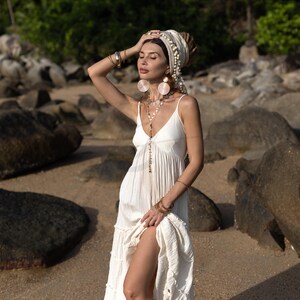 Savita is a tiered boho wedding dress that embodies simplicity and spirit. Made from undyed raw cotton, this maxi gown features a deep V neckline, smocked back for comfort, and adjustable straps to flatter small to plus sizes. Lightweight and unlined, it moves like a breeze across warm sand, making it the perfect bridal gown for beach elopements, bohemian rituals, or sacred union ceremonies rooted in natural beauty and slow fashion values.
