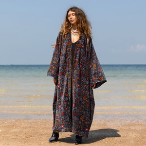 Puede incluir: Una larga bata azul con estampado floral, manga larga y cuello amplio y abierto. La bata está hecha de una tela suave y aterciopelada.