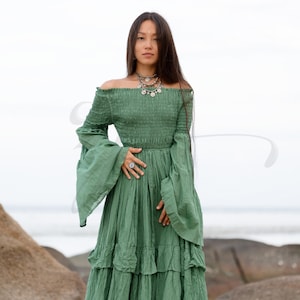 A bestselling handmade boho dress designed for weddings and goddess ceremonies, the Lucia Maxi in Elderfern Green features a soft, smocked bodice, layered skirt, and wide bell sleeves. Made from raw cotton for breathability and movement, it offers a flattering pullover fit that embraces curves. Ideal for maternity shoots, woodland elopements, or soulful rituals beneath the stars or trees.