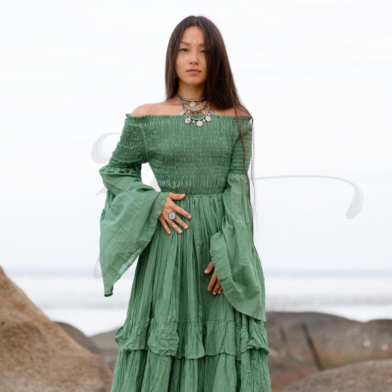 A bestselling handmade boho dress designed for weddings and goddess ceremonies, the Lucia Maxi in Elderfern Green features a soft, smocked bodice, layered skirt, and wide bell sleeves. Made from raw cotton for breathability and movement, it offers a flattering pullover fit that embraces curves. Ideal for maternity shoots, woodland elopements, or soulful rituals beneath the stars or trees.