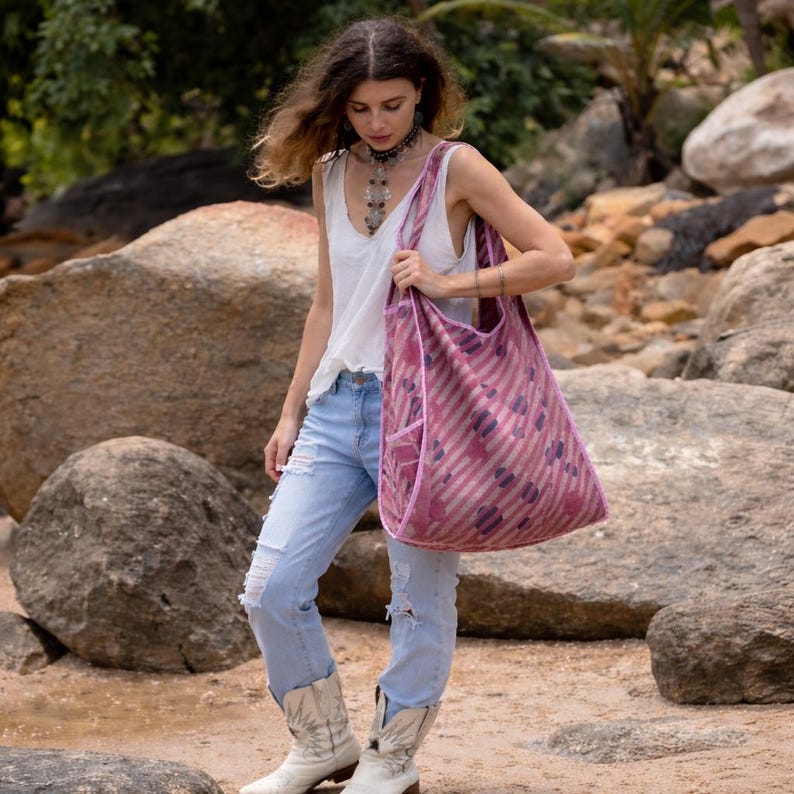 Model wearing the Dusty Rose Polka Kantha hobo bag over the shoulder, showing the relaxed slouchy silhouette and soft body-molding drape. Reversible vintage cotton quilt tote with artisan stitching and wide comfort strap for everyday bohemian wear.