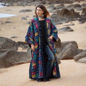 Puede incluir: Un abrigo largo tipo duster de estilo patchwork abierto por delante, con diversos paneles de tela rectangulares en tonos azul oscuro, granate, verde azulado y amarillo mostaza. La prenda incluye una hilera de botones forrados.