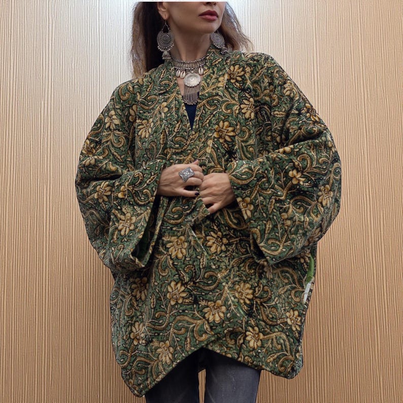 Close-up of emerald green and gold floral velvet kimono jacket showing detailed hand block print, rich texture, and artisan craftsmanship, accessorized with layered silver jewelry.
