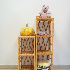 May include: Two wicker shelves with a pumpkin on the top shelf of the left shelf, a stuffed animal on the top shelf of the right shelf, and a pair of slippers on the bottom shelf of the right shelf.
