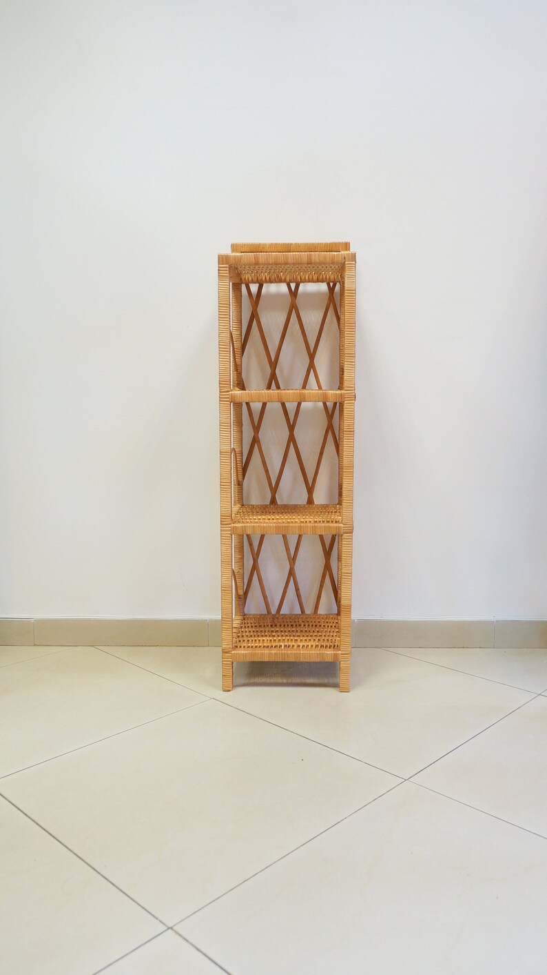 May include: A natural woven wicker shelf unit with three shelves. The shelf unit is made of light brown wicker and has a diamond pattern on the sides.