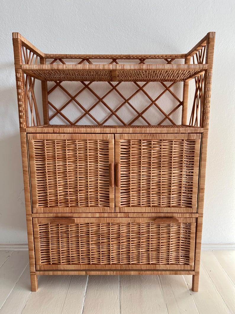 May include: A wicker cabinet with two doors and two drawers. The cabinet has a woven design and a natural wood finish.