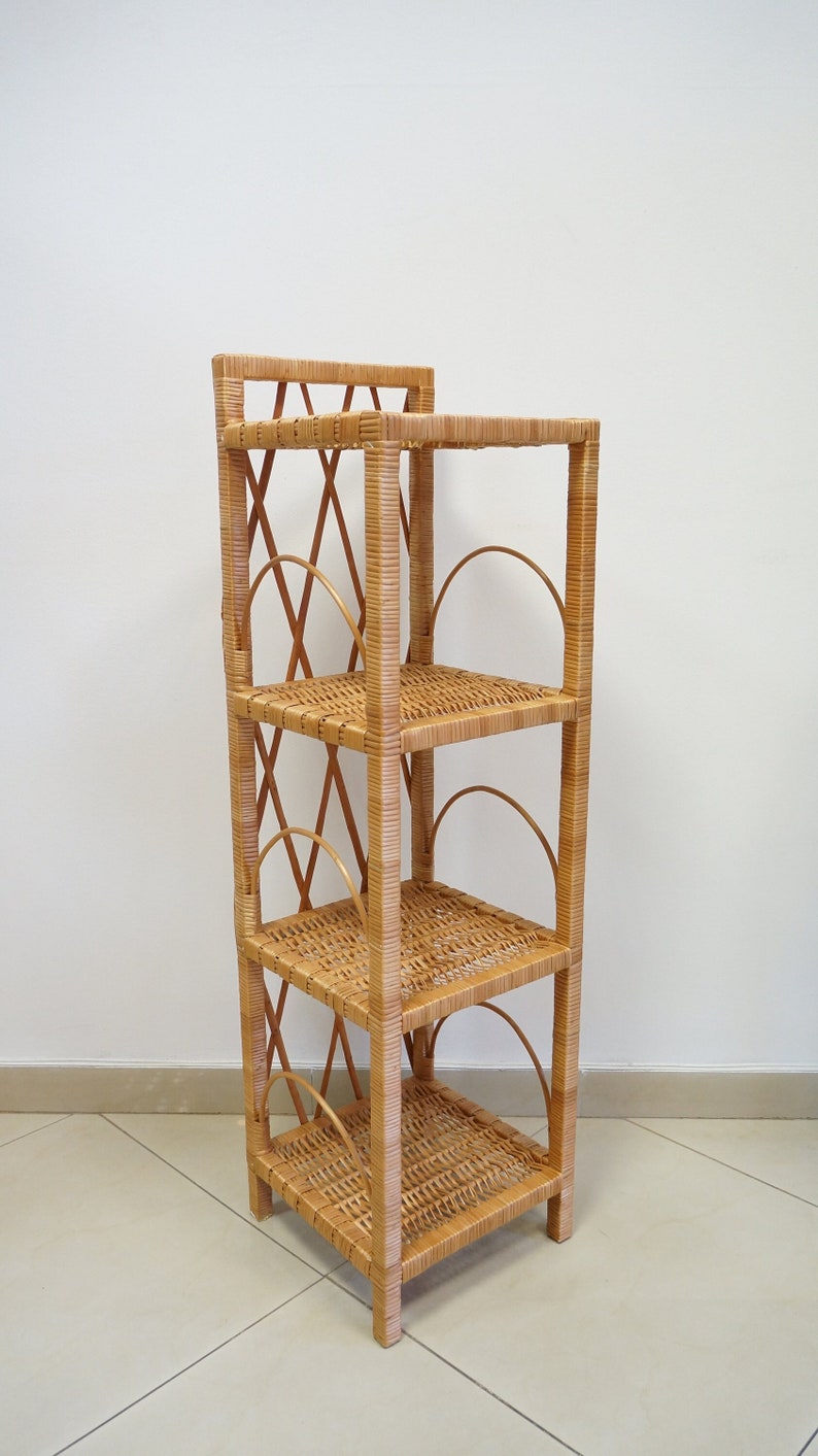 May include: A natural woven wicker shelf unit with four shelves. The shelves have a decorative woven design and are supported by a sturdy frame.