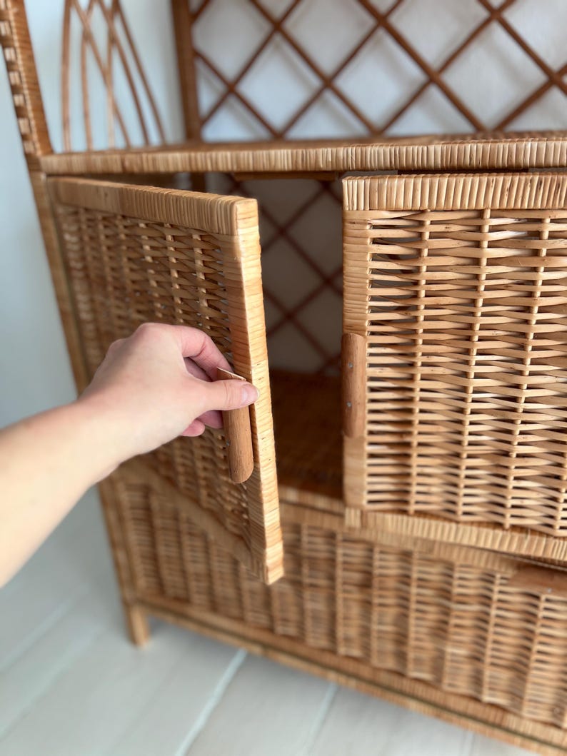 May include: A wicker cabinet with a door that is open. The cabinet has a woven design and a natural wood color.