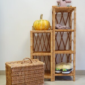 May include: Two wicker shelves with a pumpkin on the top shelf, a stuffed animal on the top shelf of the taller shelf, and a pair of slippers on the bottom shelf of the taller shelf.