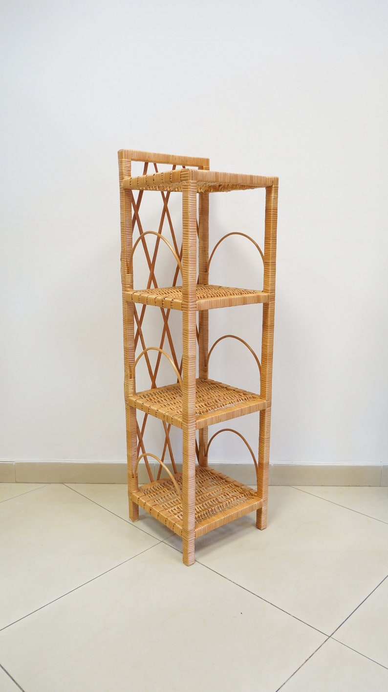 May include: A four-tiered wicker shelf unit with a natural brown finish. The shelf has a woven design and rounded edges.